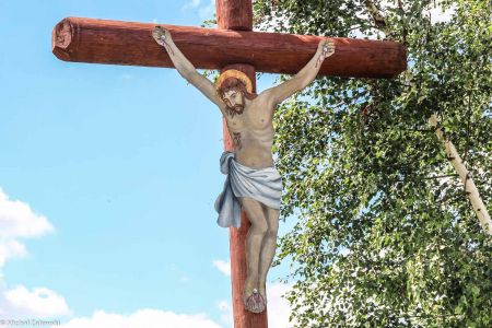 Drewniany krzyż przydrożny z Jezusem malowanym na blasze w Mieszkowicach koło Prudnika