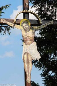 Jezus malowany na blasze na krzyżu przydrożnym w Wołowie